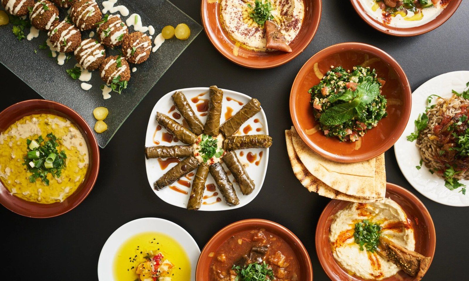 Table de mezzés vue du dessus : falafels, feuilles de vigne, hummus, tabouleh et pain libanais