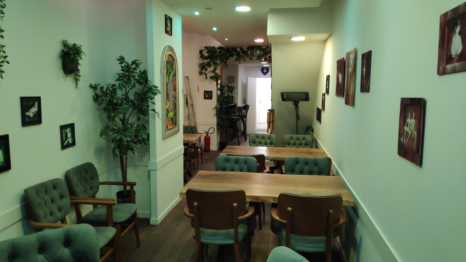 Enfilade de tables en bois et fauteuils verts dans le restaurant