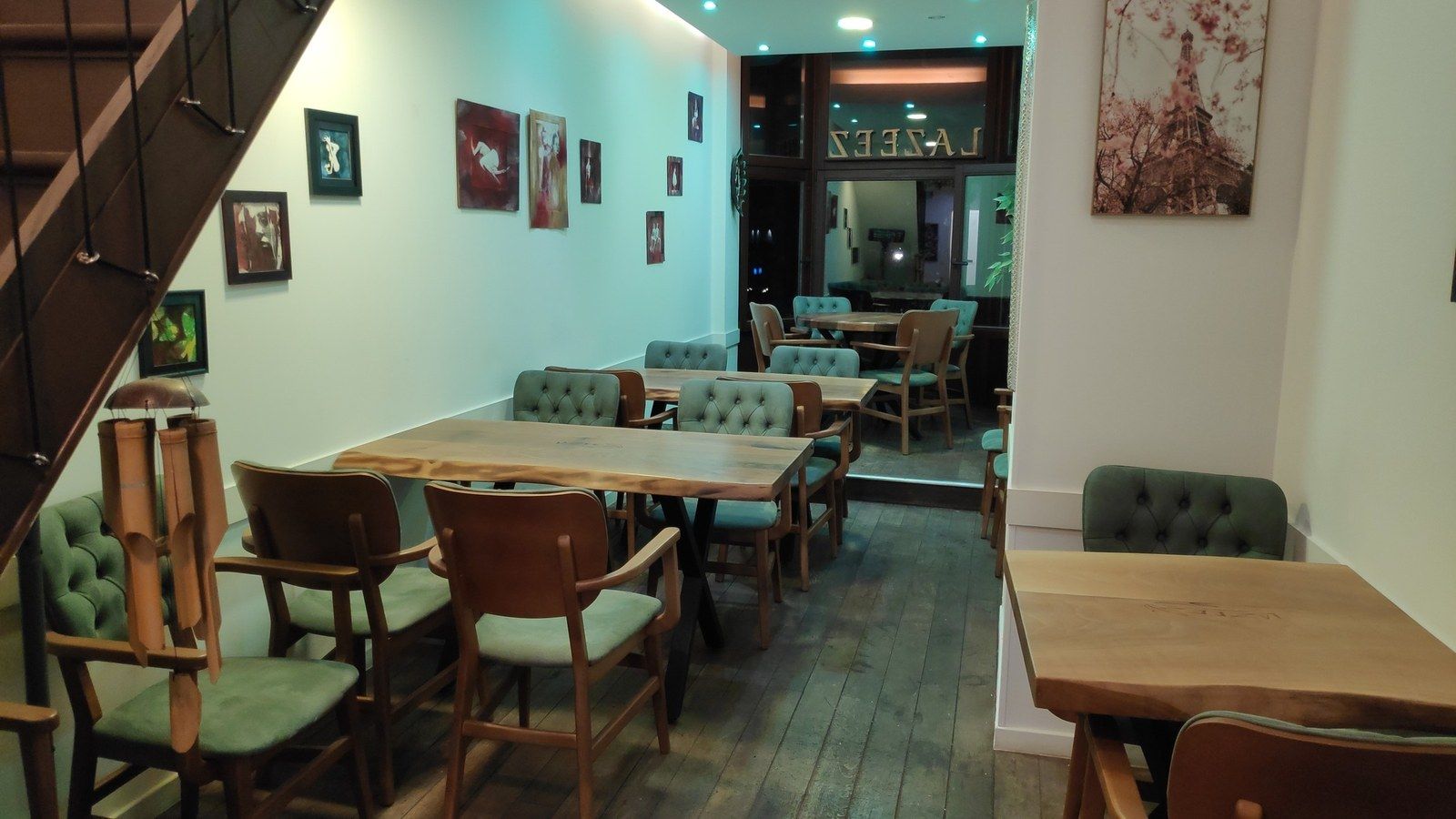 Salle avec tables en bois et fauteuils capitonnés verts